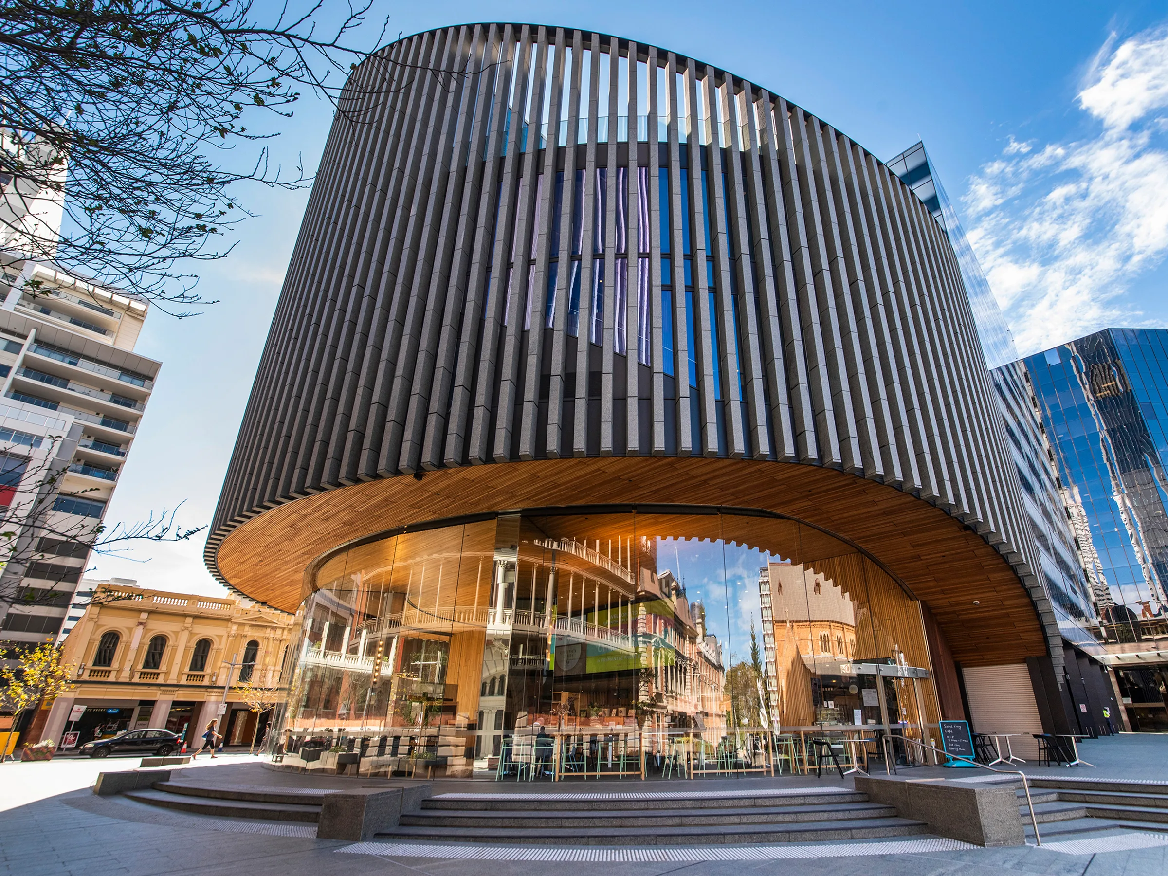 An elliptical library clad in vertical fins over a glazed ground floor