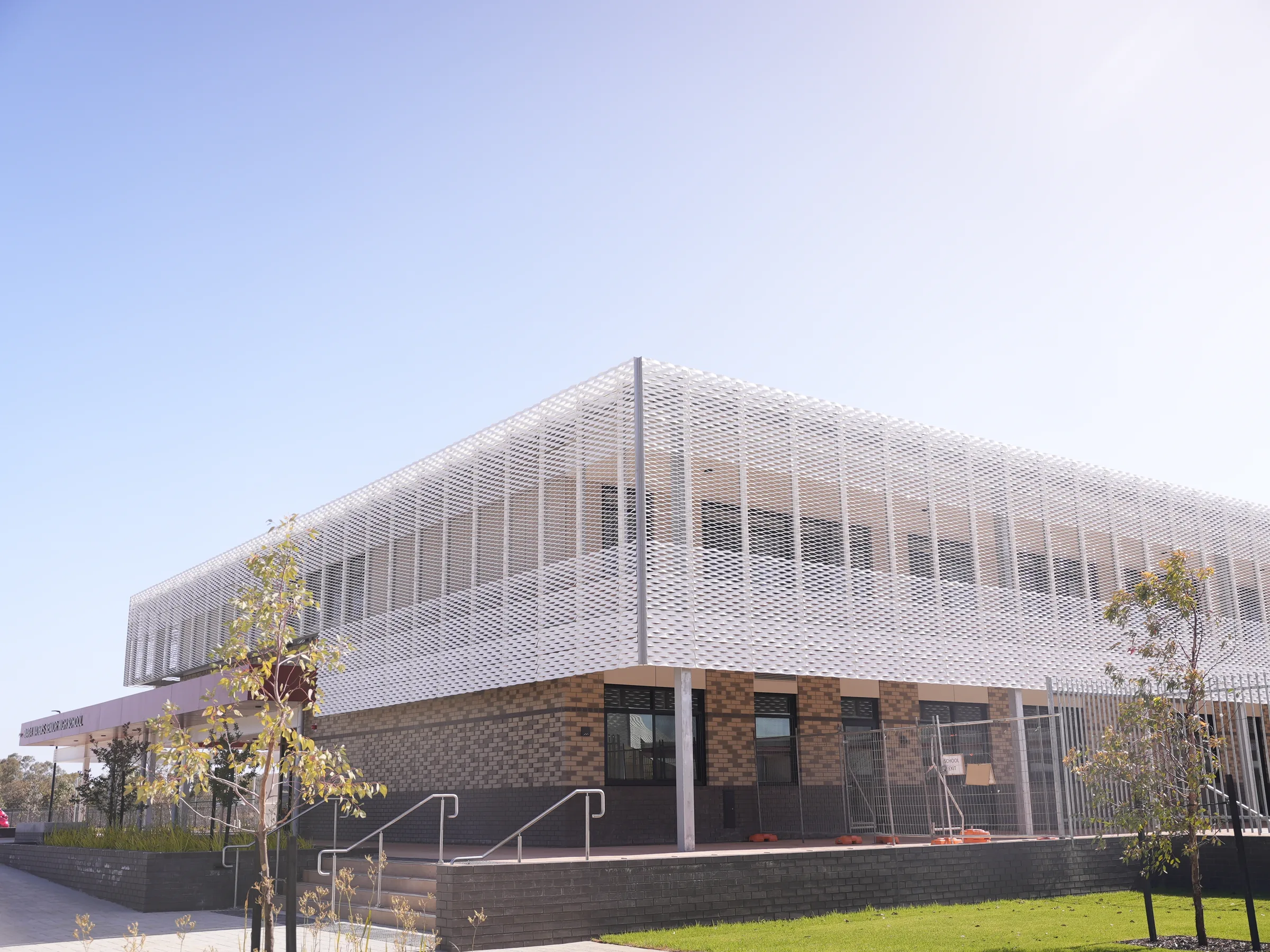 A diamond-patterned expanded mesh screen wrapping the upper storey above a brick base